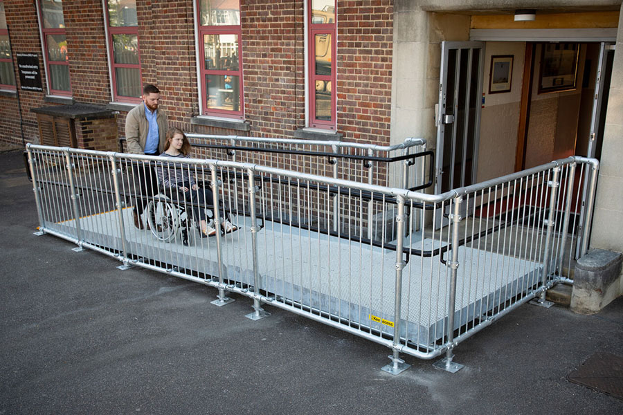 woman being pushed up a wheelchair ramp