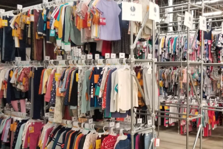 several rows of industrial clothing racks full of children's clothing