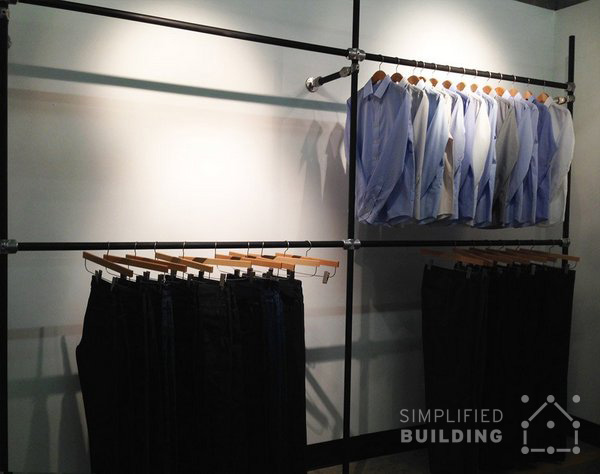 Black clothing racks with suit pants and dress shirts
